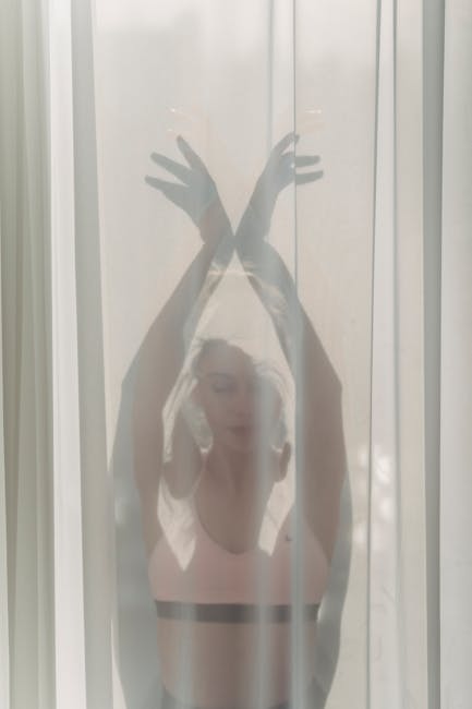 Woman performing a gentle stretching pose in a bright, peaceful room